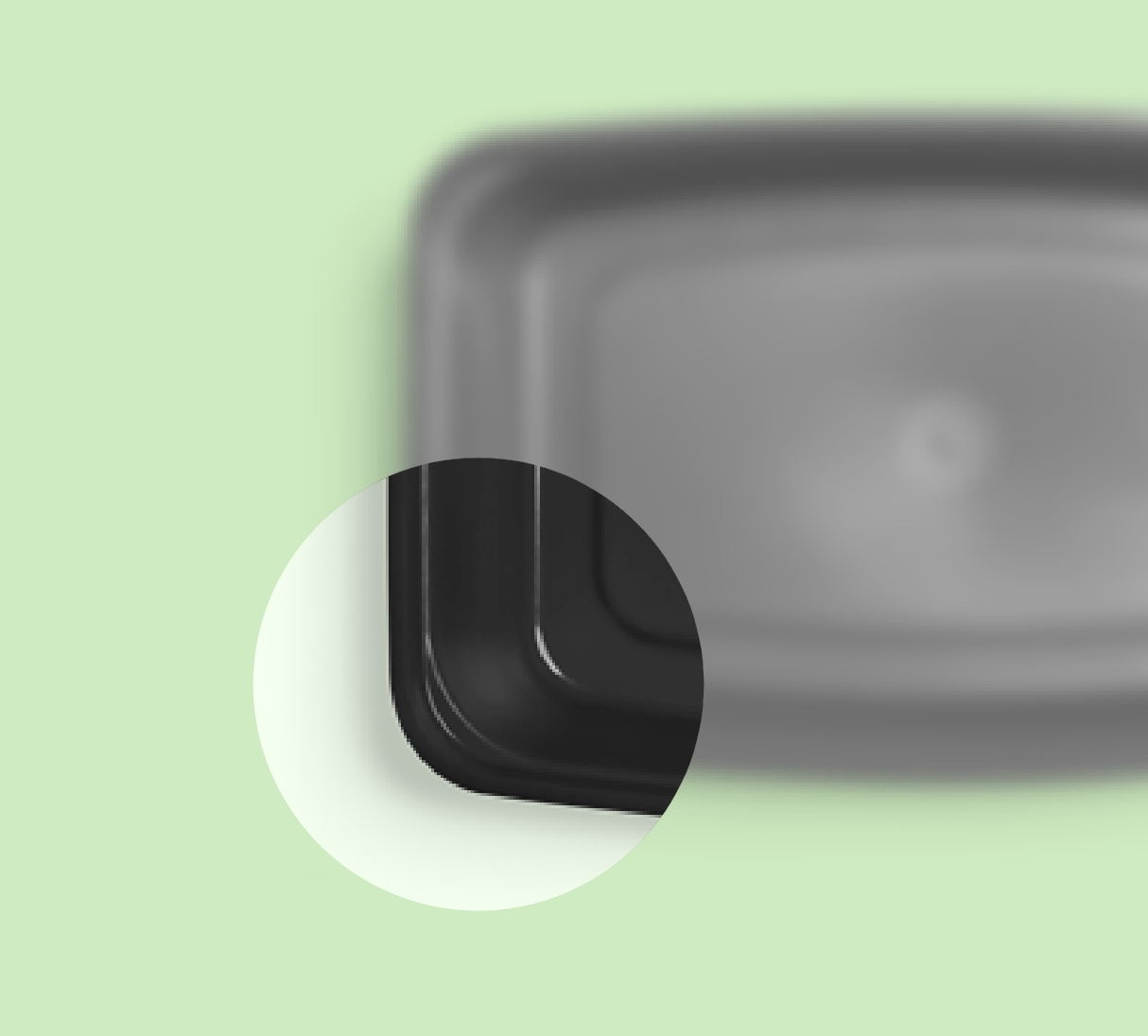 A close-up view of a black rectangular container lid on a light green background, with emphasis on the rounded corner.